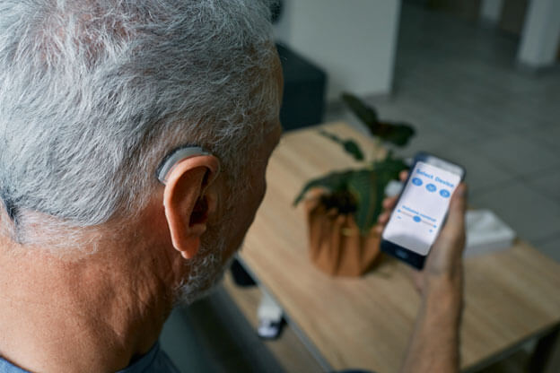 Man using his phone to control levels of his hearing aid