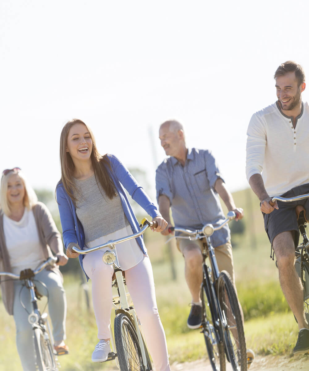 A family of 4 smiling on a bicycles outside